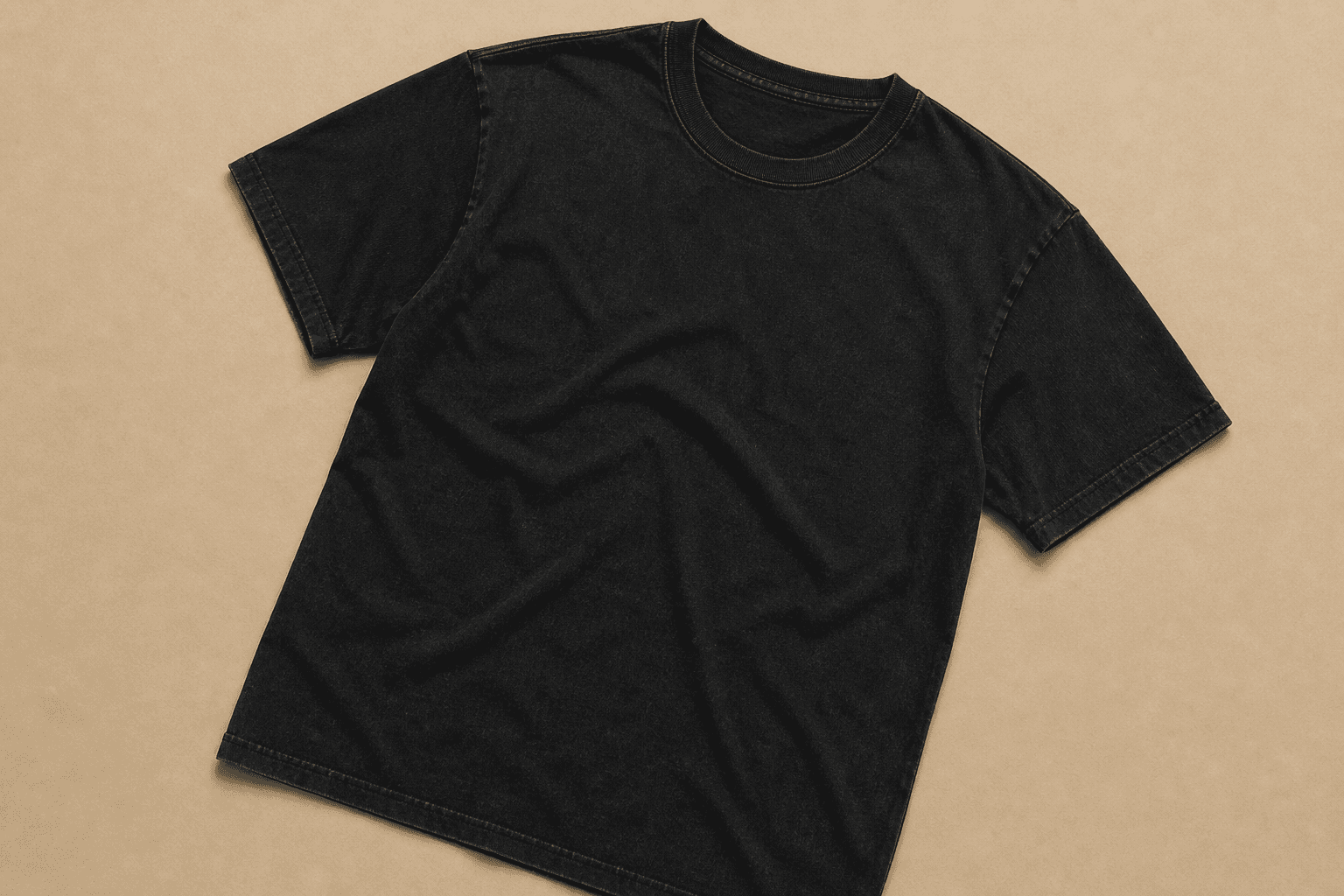 Vintage washed black t-shirt on warm sand background